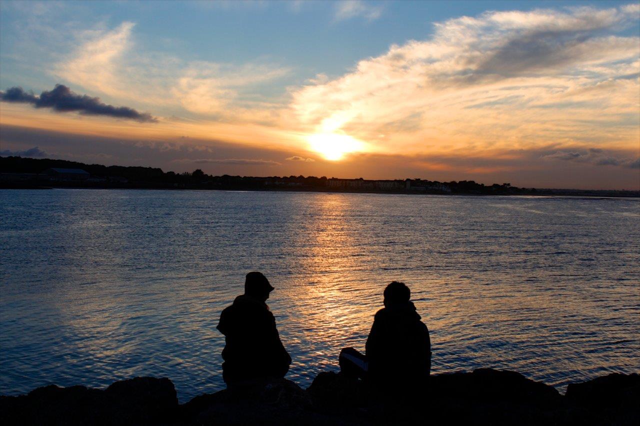 2 people sitting as the sun sets