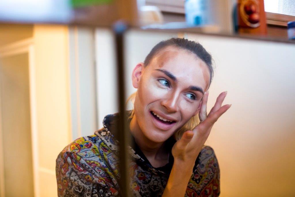 Young person applies make up in front of mirror