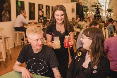 Two people being served juices in a busy cafe.