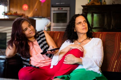 Young person and parent sat on sofa with blanket-wrapped baby